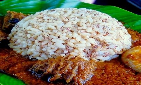 A plate of rice and meat on a green leaf.