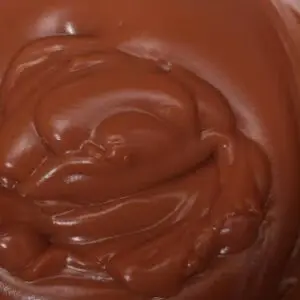 A close up of chocolate frosting in a bowl