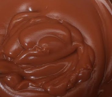 A close up of chocolate frosting in a bowl