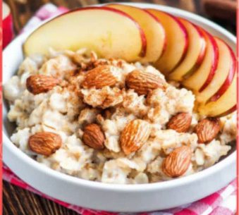 A bowl of oatmeal with almonds and sliced apples.