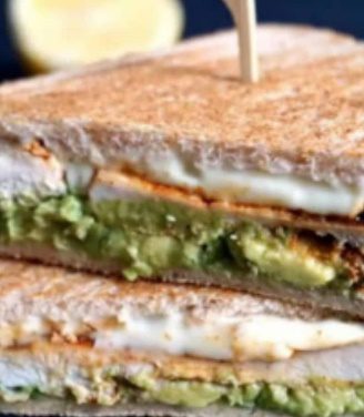 A sandwich cut in half with avocado and egg on it.